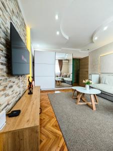 een woonkamer met een flatscreen-tv op een bakstenen muur bij Apartman Julija in Donji Milanovac