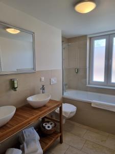 een badkamer met 2 wastafels, een bad en een toilet bij Hotel Burg Wanzleben in Wanzleben