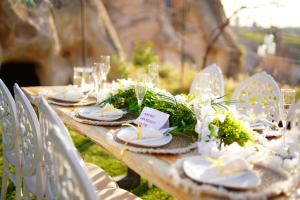 een lange houten tafel met borden, glazen en bloemen bij Anatelein Boutique Cave Hotel in Uchisar