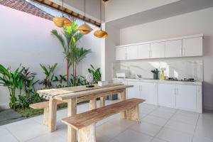 uma cozinha com uma mesa de madeira e um banco em Villa Santi - New & Modern 2 Bedroom Villa Seminyak em Seminyak