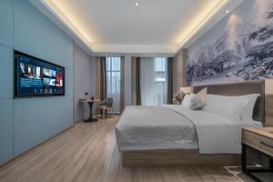 a bedroom with a large bed and a flat screen tv at Morning Hotel, Poyang Sports Center in Boyang