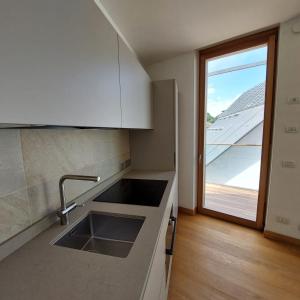 a kitchen with a sink and a large window at Appartamento vista Muse con parcheggio privato gratuito in Trento