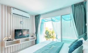 a bedroom with a bed and a tv and a window at Baan Sailboat Beach Kohlarn in Ban Kraek