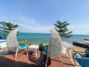 a patio with two chairs and a table and the ocean at Baan Sailboat Beach Kohlarn in Ban Kraek