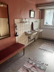 uma casa de banho com 2 lavatórios e um espelho em Rosenlund Gods - kælder B&B em Sakskøbing