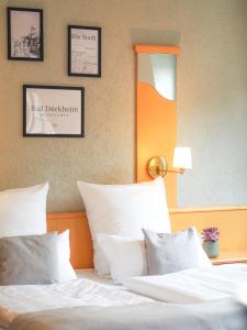 um quarto com uma cama com lençóis brancos e almofadas em Weinstraße No 8 "Einfach-Gut-Übernachten" em Leinsweiler