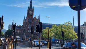 a large building with a clock tower on a city street at St Pancras Private Rooms in London