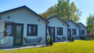 a row of houses with chairs in a yard at Domki Letniskowe Sarbilove in Sarbinowo
