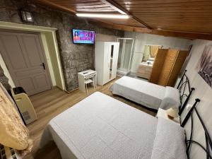 1 dormitorio con 2 camas y TV en la pared en Rural El Bosque en Entrambasaguas