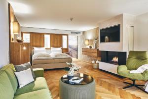 een woonkamer met een bed, een bank en een tv bij Hotel Deimann in Schmallenberg