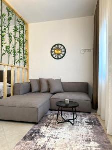 een woonkamer met een bank en een klok aan de muur bij Luxury Apartments in City Center in Durrës