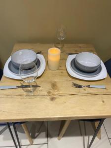 a wooden table with plates and a glass of orange juice at Suite near City, Science Park & Marshalls and close to Riverside walks in Milton