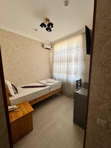 a small room with a bed and a window at Qamar Hotel in Bukhara