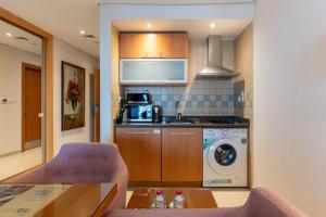 a kitchen with a microwave and a washer and dryer at Grand Bellevue Hotel Apartment Dubai in Dubai