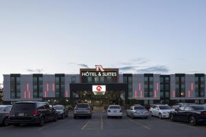 un parking avec des voitures garées devant un bâtiment dans l'établissement Hôtel & Suites Normandin Québec, à Québec