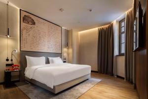 a bedroom with a white bed and a large wall at Radisson RED Tbilisi in Tbilisi City