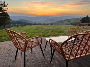 three chairs and a table on a deck with a view at Chaty w chmurach in Komańcza +9 photos
