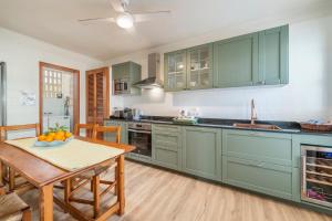 una cocina con armarios verdes y una mesa con un bol de fruta en Villa Magraner by Sealand Villas, en Can Picafort 19 fotos más