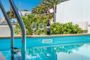 uma garrafa de vinho e copos sentados ao lado de uma piscina em Villa Magraner em Can Picafort