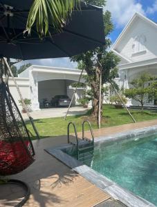 una piscina con ombrellone accanto a una casa di Villa for rent in Tra Vinh City a Xóm Vàng