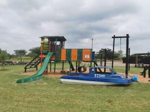 a playground with a blue boat next to a slide at Luxury Tents Belabela Resort Warmbath in Bela-Bela