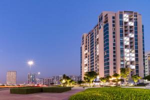 a tall building with a city skyline in the background at Abidos Hotel Apartment Dubai Land in Dubai