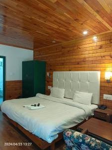 a bedroom with a large bed in a wooden wall at Highland Heritage cottages in Manāli