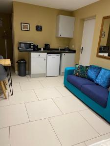 a living room with a blue couch and a kitchen at Suite near City, Science Park & Marshalls and close to Riverside walks in Milton