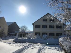 a house covered in snow with the sun behind it at Ferienwohnung Hoacherer-Hof in Riedenburg