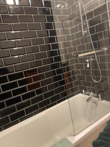 Das Bad ist mit einer Badewanne mit einer Dusche ausgestattet. in der Unterkunft Two bedroom ground floor apartment with garden in Falkirk