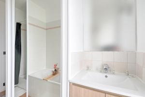 La salle de bains blanche est pourvue d'un lavabo et d'une douche. dans l'établissement La Vie en Rose - Paris - A 5 min de Paris, à Saint-Maurice