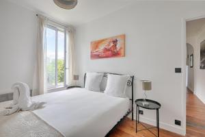 - une chambre blanche avec un grand lit et une fenêtre dans l'établissement La Vie en Rose - Paris - A 5 min de Paris, à Saint-Maurice