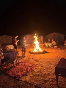 a group of people standing around a camp fire at Bivouac Dune Iriki in Foum Zguid