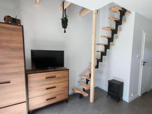 ein Wohnzimmer mit einem TV und einer Holztreppe in der Unterkunft Osada Mrożynka in Rebiszów