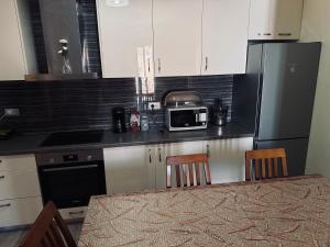 eine Küche mit weißen Schränken und einem schwarzen Kühlschrank in der Unterkunft Family Apartaments in Sarandë