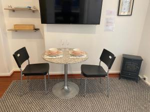mesa con 2 sillas y TV en la pared en Tree Lights Stay - Relaxing, Private Guest Suite, en Perth