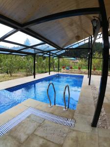 a swimming pool under a metal roof with a swimming poolvisor at Highland Heritage cottages in Manāli