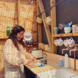 a woman standing in a kitchen preparing food at Foxglove Field Glamping in Perranuthnoe