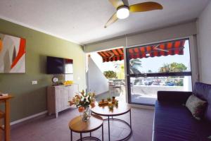 een woonkamer met een bank, een tafel en een raam bij Book Jet - Casa Adam BEACH & WIFI in Morro del Jable