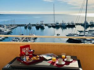 einen Tisch mit einem Tablett mit Speisen auf einem Balkon mit Yachthafen in der Unterkunft Studio VUE MER IMPRENABLE PLEIN SUD à GOLFE JUAN in Vallauris