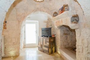 a room with a stone wall with a door and a television at Trullo dei Sogni con Piscina e Jacuzzi in San Michele Salentino