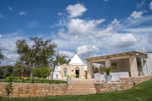 a stone building with a stone wall and a white chapel at Trullo dei Sogni con Piscina e Jacuzzi in San Michele Salentino