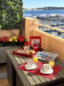 een dienblad met eten en drinken op een tafel op een balkon bij Studio VUE MER IMPRENABLE PLEIN SUD à GOLFE JUAN in Vallauris