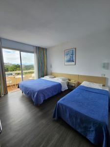 a hotel room with two beds and a balcony at Hotel du Port in Canet-en-Roussillon