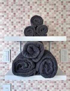 a pile of towels on a shelf in a bathroom at Maria Hotel 宇都宮 in Utsunomiya