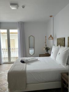 1 dormitorio con 1 cama blanca grande y ventana en Casapuerta El Refugio, en Zahara de los Atunes