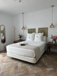 1 dormitorio con 1 cama blanca grande y 2 lámparas en Casapuerta El Refugio, en Zahara de los Atunes