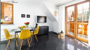 カルパチにあるWonder Home - Apartamenty z balkonami Leśny Dom II - w cichej i zielonej części Karpaczaのダイニングルーム(テーブル、黄色い椅子付)