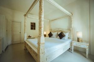 a bedroom with a white canopy bed and a table at Gili Amor Boutique Resort in Gili Trawangan