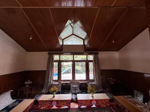 an attic room with a table and a window at Ramta Jogi Hotel & Stays in Manāli